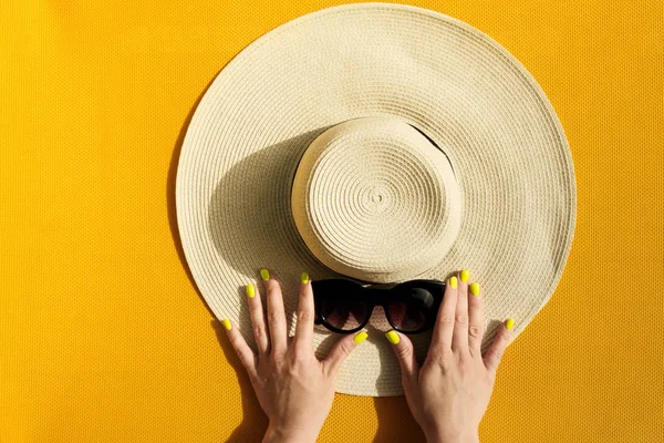 Mãos de menina segurando chapéu de palha e óculos de sol em vibrante — Fotografia de Stock