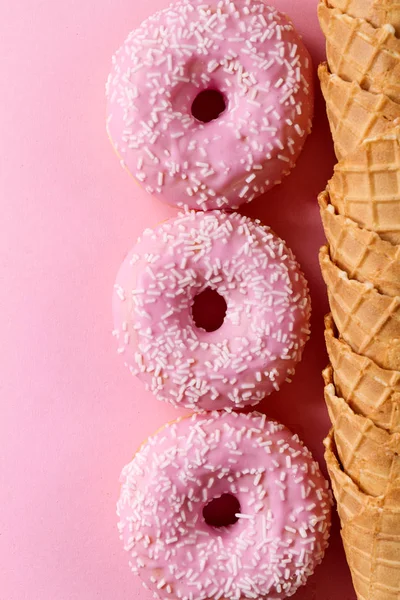 Gustose ciambelle rosa fresche glassate con coni di cialde gelato — Foto Stock