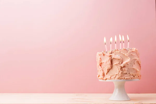 Bolo de aniversário rosa com velas acesas — Fotografia de Stock