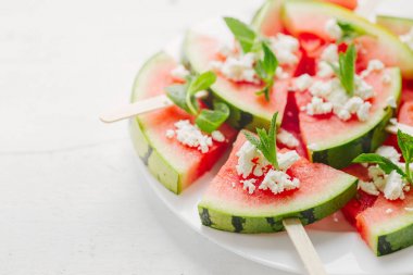  slices of watermelon on sticks topped with feta cheese and mint clipart