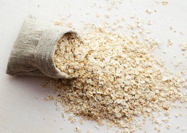 ahşap masa üzerinde çuval bezi çanta içinde yulaf ezmesi