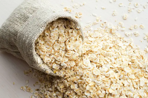 ahşap masa üzerinde çuval bezi çanta içinde yulaf ezmesi