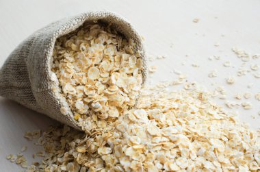 ahşap masa üzerinde çuval bezi çanta içinde yulaf ezmesi