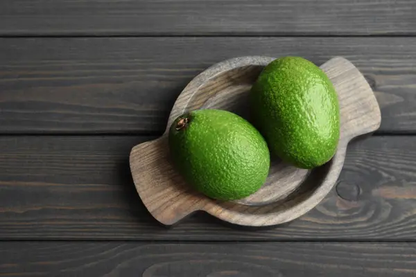 Frische Bio-Avocado im Holzteller über dunklem Holztischhintergrund — Stockfoto