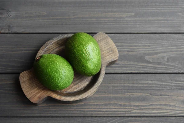 Aguacate orgánico fresco sobre fondo de mesa de madera oscura, vista superior, espacio para copiar — Foto de Stock