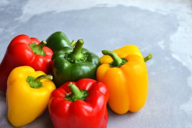 Gri taş zemin üzerinde yeşil, kırmızı ve sarı dolma biber. Organik sağlıklı yiyecekler. Boşluğu kopyala.