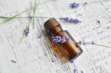 Organik bitkisel yağ ve eski ahşap arka planda taze lavanta çiçekleri.