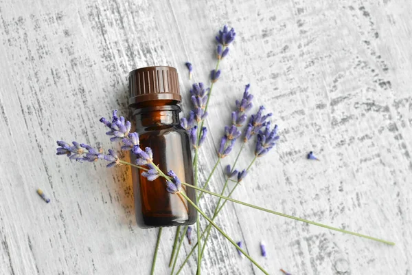 Organic herbal oil in dark glass bottle and fresh lavender flowers on old wooden table background, top view — Zdjęcie stockowe