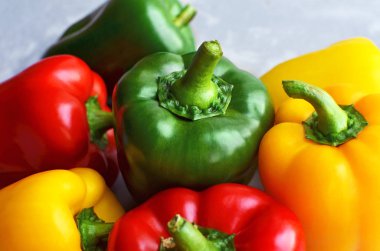 Green, red and yellow bell pepper on grey stone background. Organic healthy food