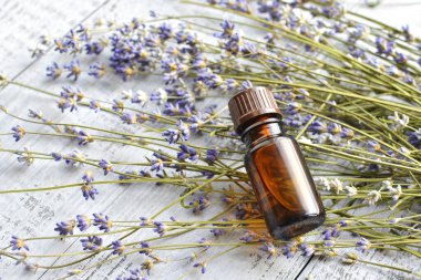 Organic lavender essential oil in dark glass transparent bottle with fresh lavender flowers on wooden background. Aromatherapy treatment.