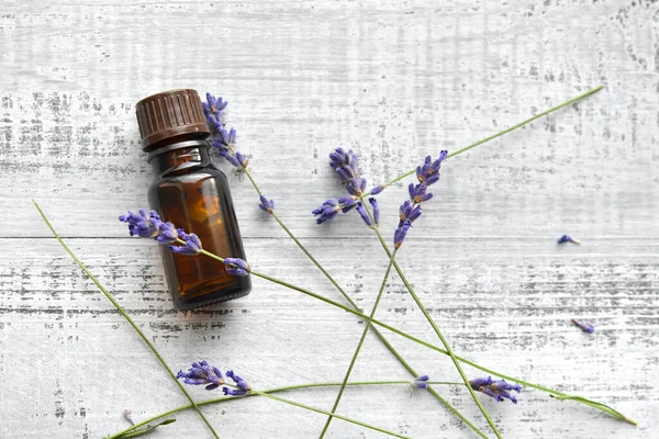 Organic lavender oil in dark glass bottle and fresh lavender flowers on old wooden background. Aromatherapy treatment. Top view, copy space. — Stock Photo, Image