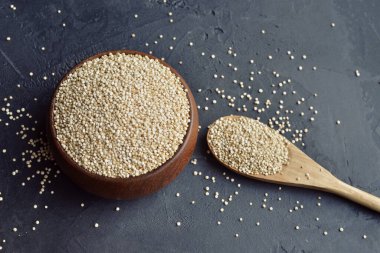 Kuru organik kinoa tohumları ahşap kasede ve kaşıkta koyu grunge arka planda, üst görünümde, boşluğu kopyala