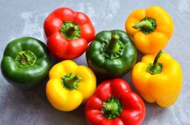 Green, red and yellow bell pepper on grey stone background. Organic healthy food
