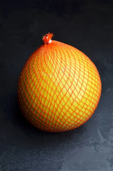 Siyah arka planda koruyucu ağa sarılı Pomelo meyvesi