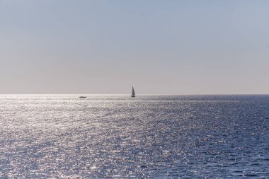 Bir tekne ile denizde yelken ufukta. Parlak güneş deniz ve kör gözler yansıtılır.