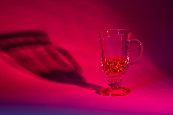 A glass of red. A glass of glass beads illuminated by red light.