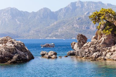 Kayalar ve küçük bir turist denizde yelkenli tekne.