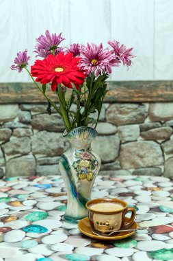 Bir fincan kahve ve bir buket çiçek masanın üzerinde. Günaydın.