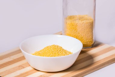 Millet beyaz arka plandaki ahşap tezgahta beyaz bir kasede homurdanıyor. İzole edilmiş resim.