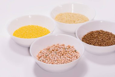 Çeşitli kuru tahıl ve fasulye arkaplanları: pirinç, bezelye, pirinç, beyaz kaselerde karabuğday. Yukarıdan bak. Beyaz arkaplanda.