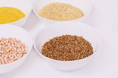 Çeşitli kuru tahıl ve fasulye arkaplanları: pirinç, bezelye, pirinç, beyaz kaselerde karabuğday. Yukarıdan bak. Beyaz arkaplanda.