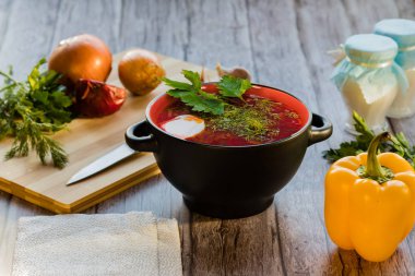 Kırmızı borç, Ukrayna mutfağının ulusal bir yemeği. Fotoğrafta Borsch, ekşi krema, yeşil soğan ve ahşap arka planda sarımsaklı siyah bir seramiktir..