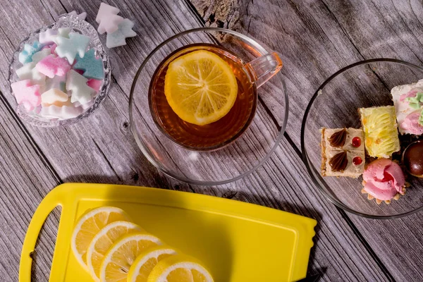 Cup of tea with lemon on a wooden table. Morning tea with lemon and pastries.