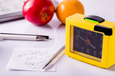 Office desk with pens, clock, note paper and tablet. Office supplies on a white background.