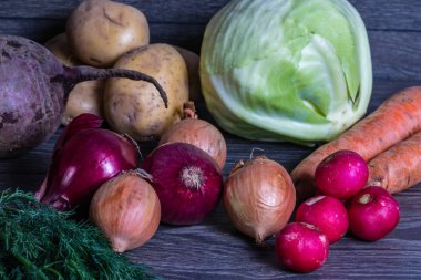Tahta bir masada farklı sebzeler. Lahana, patates, turp, soğan, havuç.