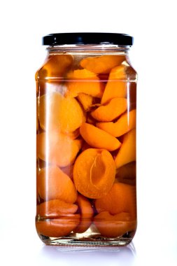 Bir kavanoz konserve kayısı beyaz arka planda kapakla kaplıdır..