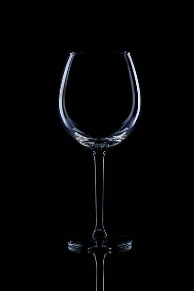 Wine glasses of different shapes and a bottle on a black background. A contour photo.