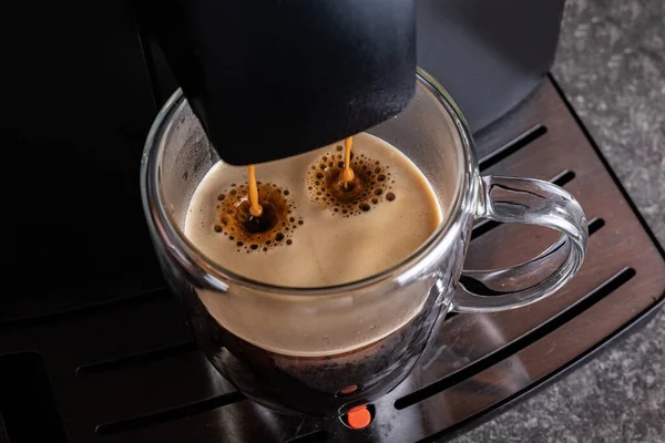 Espresso machine for making fresh coffee. Coffee is poured into a transparent Cup.