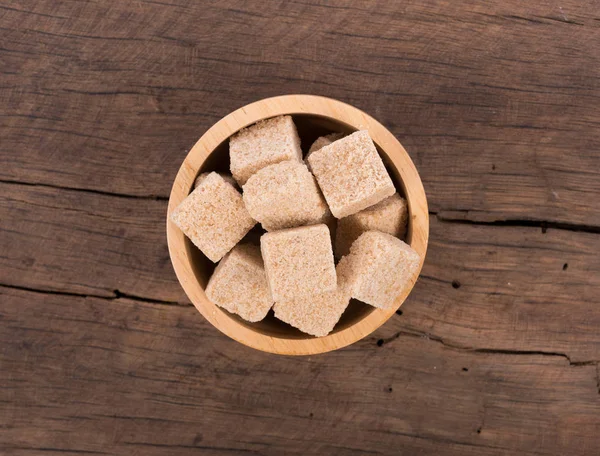 Braune Zuckerwürfel auf Holzgrund. Ansicht von oben — Stockfoto