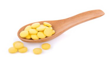 Beyaz arka planda izole edilmiş kaşıktaki haplar