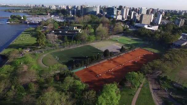 Воздушное изображение природы, теннисные корты и футбольное поле на берегу реки, камера, спускающаяся в общественный парк — стоковое видео
