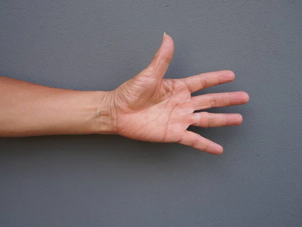 En hånd som åpner håndflaten på grå bakgrunn – stockfoto