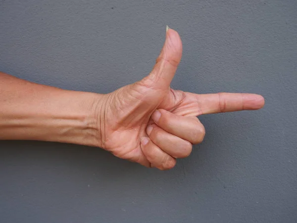 A hand making a shape of a pointing hand on gray background — Stock Photo, Image