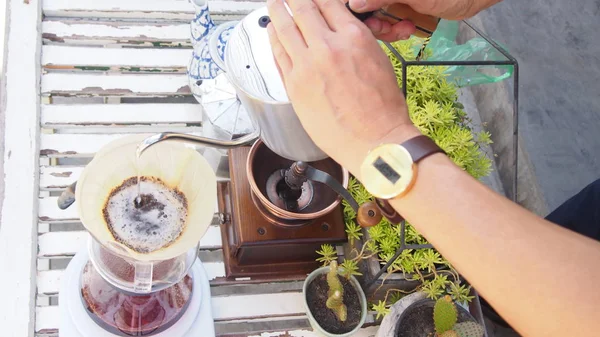 hand drip coffee, barista pouring hot water over roasted grinded coffee powder making drip brew coffee