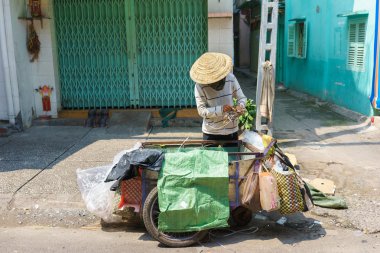 Küçük bir sokakta, Saigon, Vietnam kullanılmayan şeyleri toplama bir çöp toplayıcı