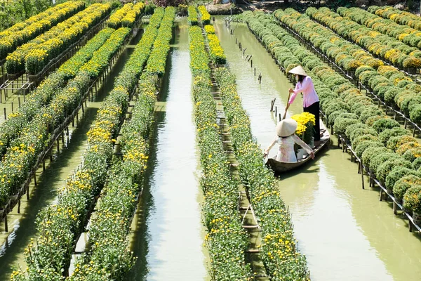Two ladies with traditional dress are in a boat at the floating flower field in Sa Dec, Dong Thap, Vietnam. Sadec (Sa Dec) is one of the biggest flower stocks in Mekong Delta. — Stock Photo, Image