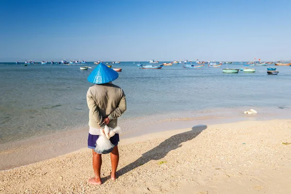 Un pescador con sombrero cónico azul en la playa My Hiep temprano en la mañana, Ninh Thuan, Vietnam. Ninh Thuan es famoso por sus hermosos paisajes, majestuosas torres Cham y su cultura única Cham . — Foto de Stock