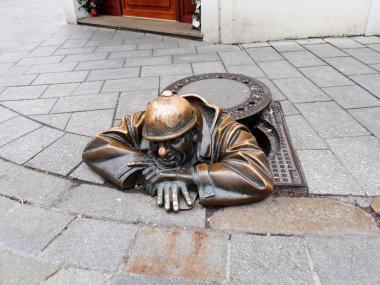 Bratislava, Slovakya - 15 Aralık 2017: bronz heykel geçenler bir kuyu üzerinden izleyen bir adamım. Cumil veya gözetmen adı ve tarihi kentin sembolü haline gelmiştir