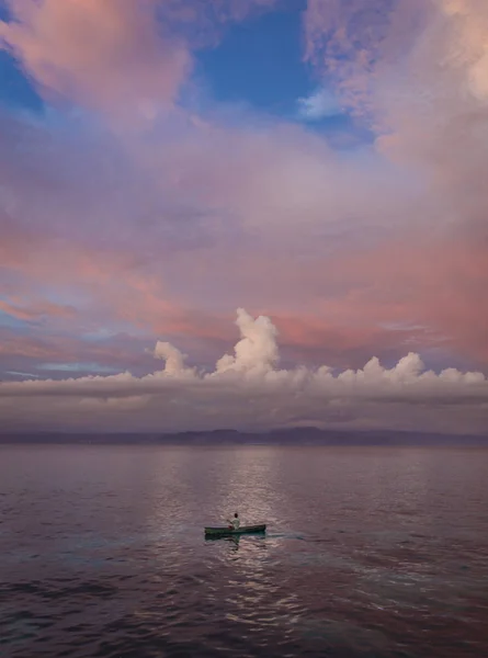 Mann rudert mit einem kleinen Kanu bei Sonnenuntergang auf der Insel Nusa Limbongan — Stockfoto