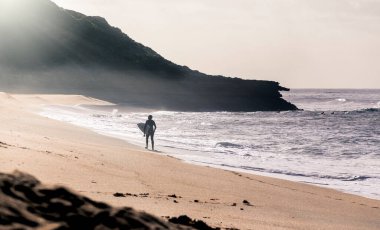 Sörfçü, Bells Beach, Torquay, Avustralya 'da sisli bir sabah suda diğer sörfçülere katılmaya hazırlanıyor.