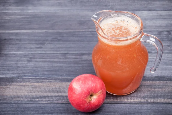 Свежий яблочный сок в кувшине на столе — стоковое фото