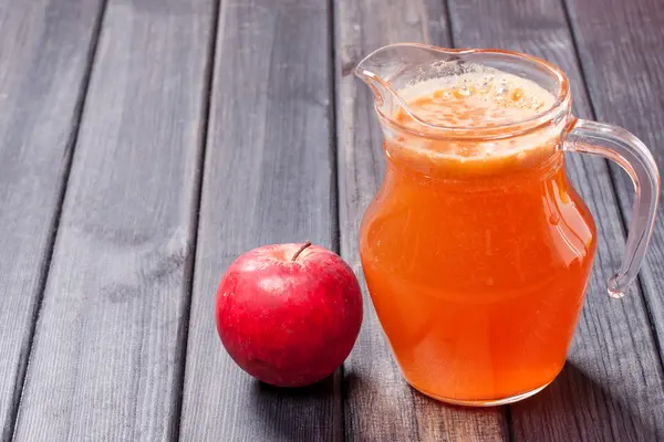 Copiar foto spase de una manzana roja y jugo fresco en la jarra en la mesa — Foto de Stock