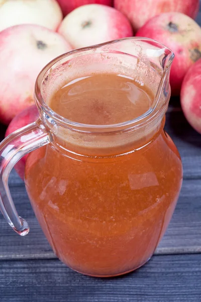 Свежий яблочный сок в кувшине на деревянном столе — стоковое фото
