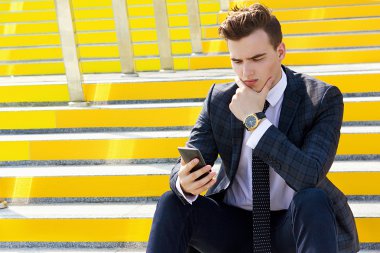 Sarı bir merdiven üzerinde oturan erkek iş adamı