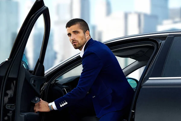 handsome businessman in a blue suit into the car