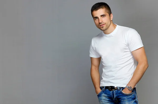 Красивый мужчина в белой футболке и джинсах — стоковое фото